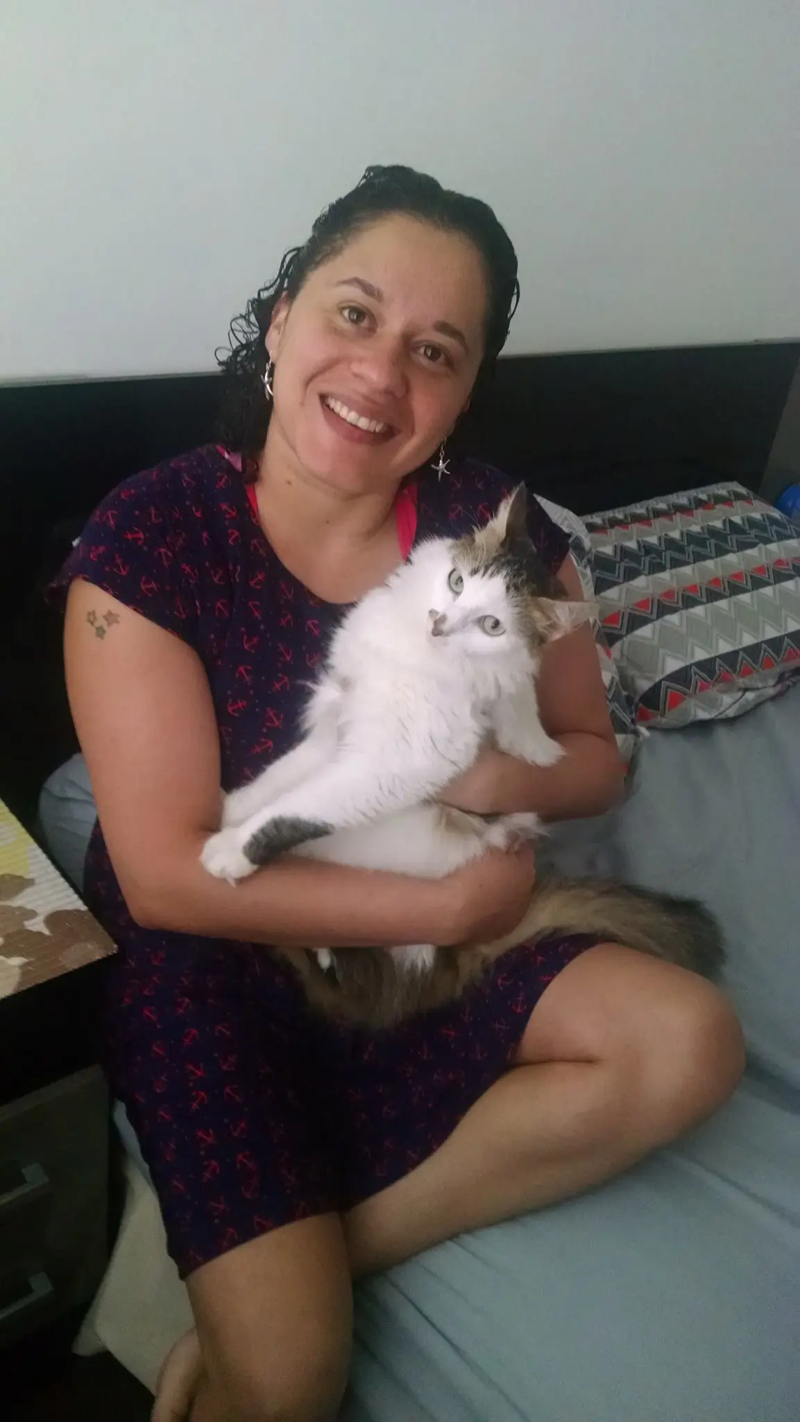 Bia teve sorte de encontrar um novo lar. Ela já tinha sido devolvida por adotante antes. Descrição para deficientes visuais: Moça sentada no sofá tem no colo uma gatinha branca de rosto cinza. A moça sorri e a gatinha está com uma carinha meiga olhando para a câmera. Foto: Arquivo pessoal