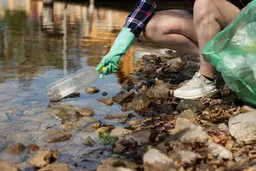 Imagem de pessoa limpando rio sujo de plástico